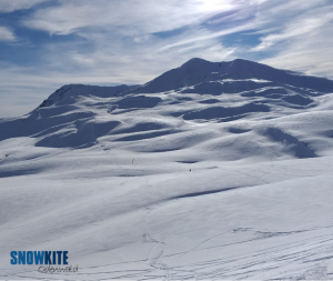 Das Bild zeigt einen roten Kite SubzeroV1 von Ozonekites auf weißem Schnee in den Bergen.