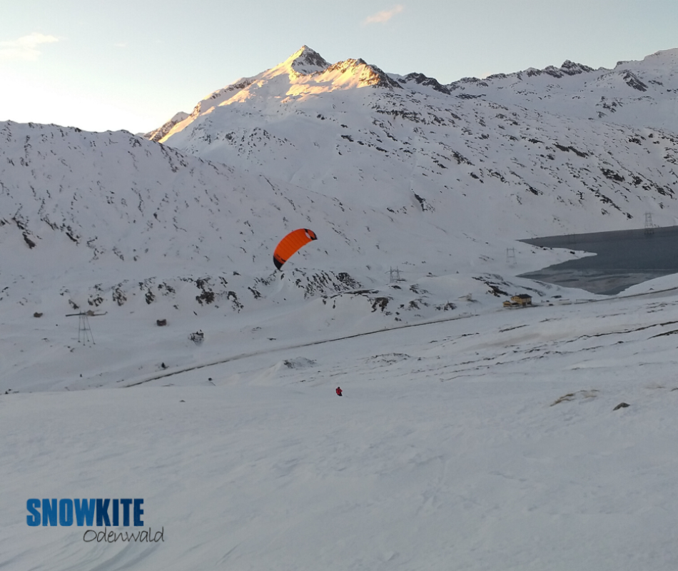 Das Bild zeigt einen roten Kite SubzeroV1 von Ozonekite vor weißem Schnee in den Bergen.