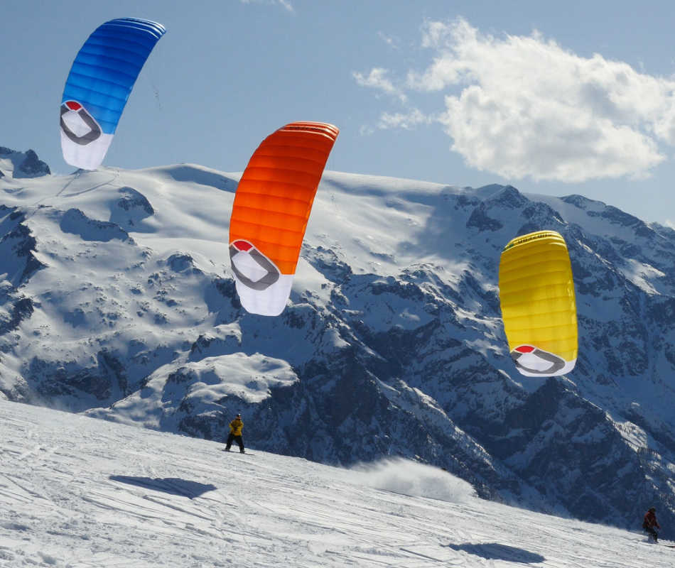 Die bunten Kites subzeroV2von Ozonekites werden durch den Wind getrieben. Sie ziehen Snowkiter mit Ski über den Schnee